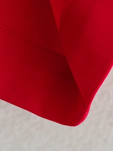 Détail de la texture du tissu rouge et des coutures précises du gilet et du pantalon