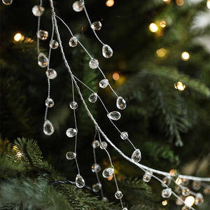 Clear crystal bead garland hanging on Christmas tree branches with festive warm lighting