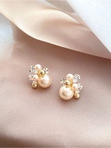 Gros plan de boucles d'oreilles fleurs en or 18k avec perles et cristaux sur soie