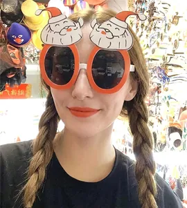 Close-up of novelty Christmas glasses featuring dual Santa Claus decor on orange frames