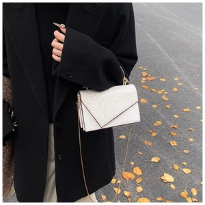 Nahaufnahme einer weißen Umschlagtasche mit silbernen Pailletten und goldener Kette