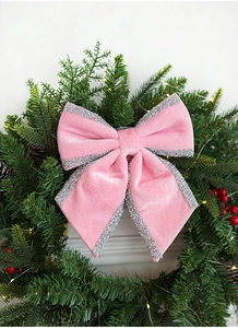 Detail view of pink velvet Christmas bow with silver glitter edges on a pine wreath