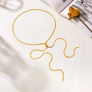 Detail shot of a golden flat snake bone necklace with a knotted design on a white background