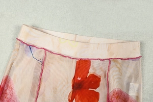 Vue détaillée du tissu en maille beige avec fleurs roses et finitions de couture surjetées