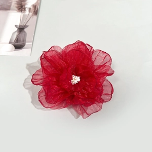 Détail d'une pince à cheveux rose en organza rouge avec perles blanches au centre