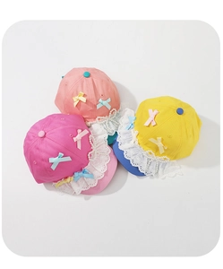 Detailed view of kids lace baseball caps with pearls and bows in pink and yellow colors