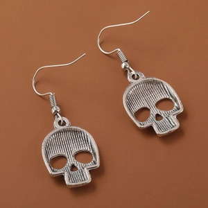 Close-up of vintage silver hollow skull drop earrings with detailed metal texture