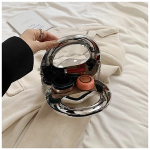 Detailed shot of transparent acrylic round clutch bag with silver chain and cosmetics