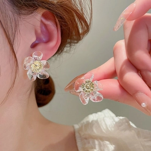 Macro detail of clear resin flower earrings with golden core and wavy petal texture