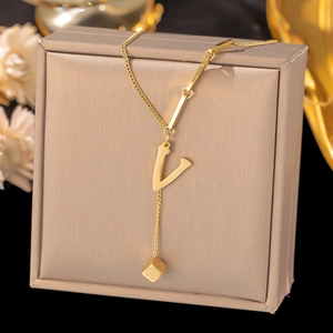 Close-up of golden V-shape pendant necklace with square cube charm on a jewelry box