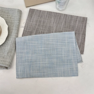 Detail of woven rectangular placemats in blue, brown, and grey with textured fabric finish