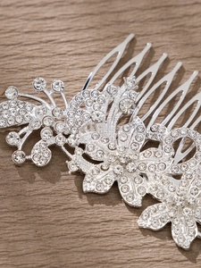 Nahaufnahme eines silbernen Haarkamms mit glitzernden Kristallen und floralem Blattdesign