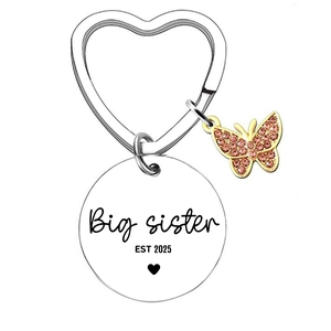 Gros plan du pendentif Big Sister EST 2025 avec charm papillon et anneau en forme de cœur