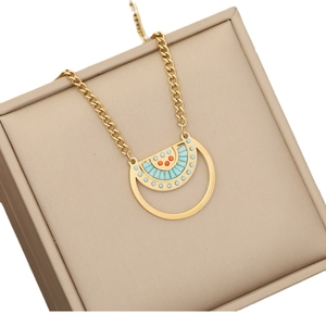 Golden fan-shaped necklace with blue and orange crystals on a beige jewelry box lid
