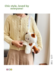 Close-up of calico cat plush crossbody bag with heart patch worn by a model in sweater