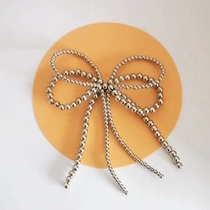 Detail von silbernen Perlen-Schleifen-Schuhclips mit metallischem Glanz auf rundem Pad