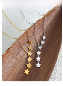 Detailed view of star tassel necklace in gold and silver finish on wood texture