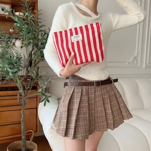 Close-up of red and white striped toiletry bag with today thanks label in hand
