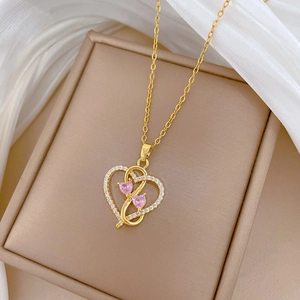 Detail view of heart and infinity pendant with pink gems on elegant beige box