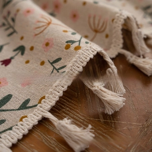 Close-up of cotton linen tablecloth with floral patterns and delicate white tassel edge