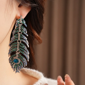 Macro view of vintage peacock feather earrings with colorful rhinestones on a model