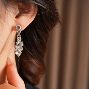 Close-up of geometric diamond earrings worn by a model in warm lighting ambiance