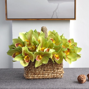 Artificial yellow-green Cymbidium orchids with red centers in a rustic woven basket