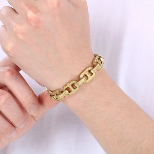 Dettaglio di un bracciale a catena dorata stile punk indossato al polso su tessuto