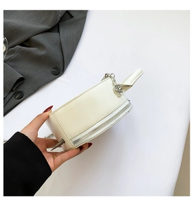 Close-up of white leather round handbag with unique silver metal cone spike detail