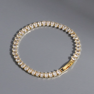 Macro detail of gold tennis bracelet with pear-cut cubic zirconia and secure clasp