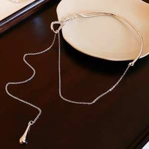 Detail of silver dual-layer necklace with water drop pendant on elegant white ceramic dish