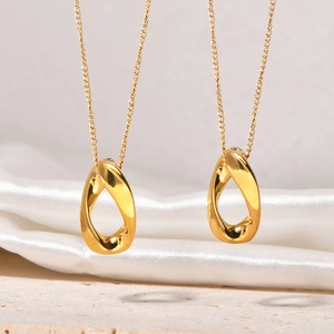 Détail macro de deux pendentifs goutte d'eau dorés sur un fond élégant en soie blanche