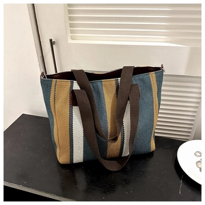 Detailed view of striped canvas tote bag with woven texture and brown handles