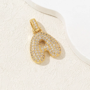 Gold-plated chunky letter A pendant with pave-set zircon stones on textured background