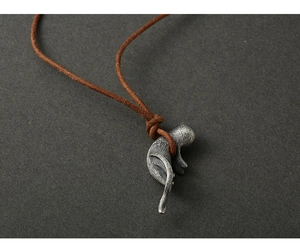 Macro detail of vintage 925 silver cat pendant with textured brown leather cord