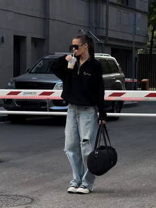Detail of zip-up sweatshirt with letter print paired with baggy jeans and sneakers