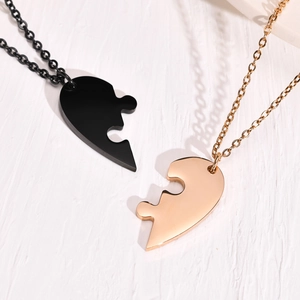 Close-up of black and gold titanium steel heart pendants on a white textured background
