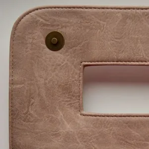 Detail of nude pink faux leather crossbody bag with bronze magnetic buckle and handle cutout