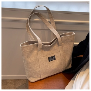 Detailed view of heavy canvas tote bag texture with fashion label on beige fabric