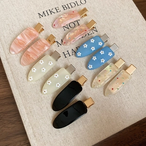 Set of ten colorful resin hair clips with marble finish and daisy patterns on beige background