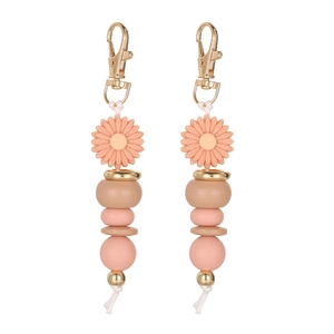 Detail of pink beaded daisy keychain with golden clasp and white tassel on white background
