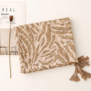 Detailed close-up of khaki zebra print scarf with gold foil accents and tassel edges