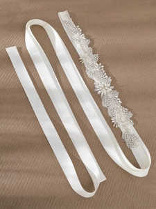 Close-up of bridal crystal applique belt featuring intricate pearls and rhinestones on satin