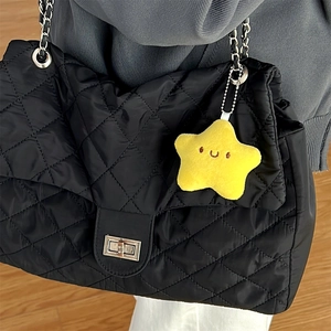 Detalle de llavero de estrella de peluche amarillo en bolso acolchado negro con cadena