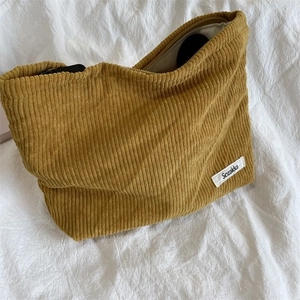 Detail of ginger corduroy makeup bag texture with brand label on a soft fabric background