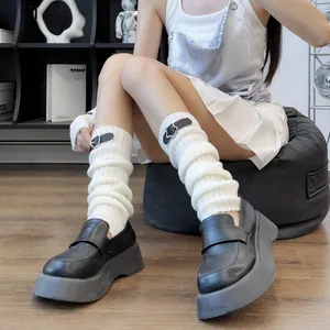 Close-up of white knit leg warmers with black star belts and chunky platform loafers
