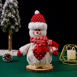 Detail of Christmas snowman plush figure with red polka dot hat on natural wood base