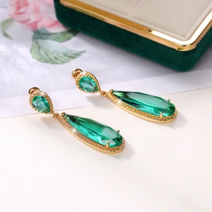 Macro view of long emerald pear-cut drop earrings with sparkling cubic zirconia halo