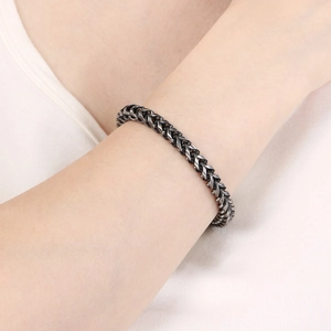 Gros plan d'un bracelet gourmette en acier inoxydable vintage porté au poignet
