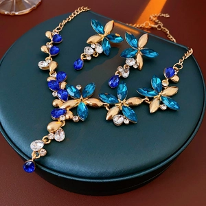 Close-up of vintage flower jewelry set with blue crystals on a green display stand